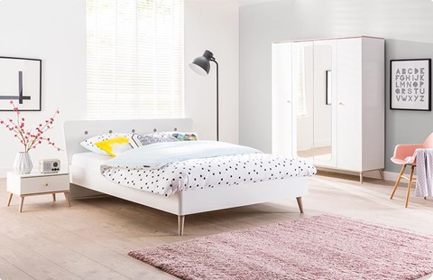 een bed met een roze kleed en een lamp