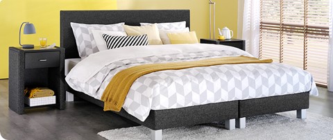 een bed met gele en grijze kussens