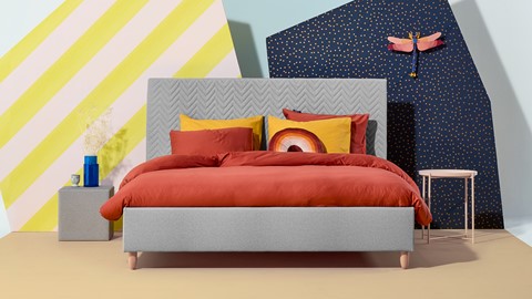 een bed met oranje lakens en kussens