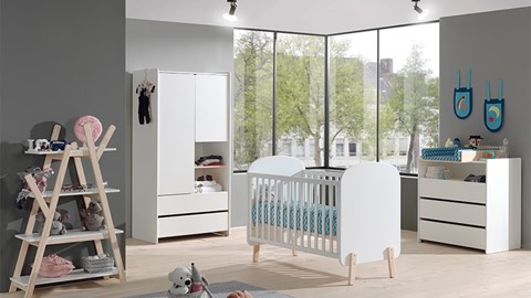 een babykamer met een wieg en een commode