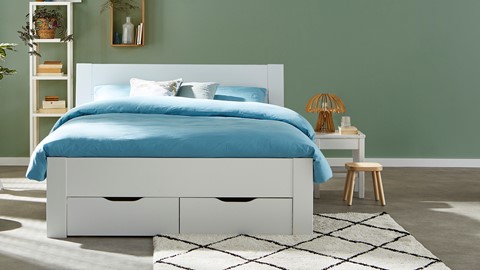 een bed met lades en een kruk in een kamer