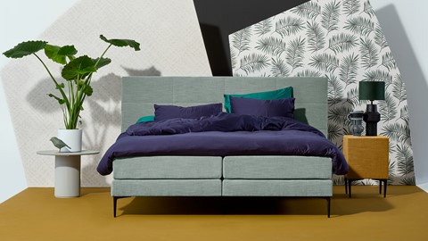 een bed met paarse lakens en kussens