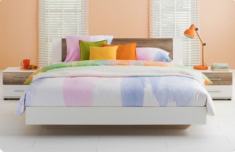 een bed met kleurrijke kussens en een lamp