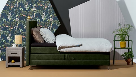 een bed met kussens en een groen hoofdeinde