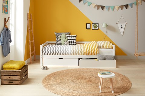 een geel-witte slaapkamer met een bed en een kleed
