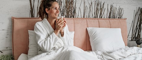 Een vrouw in een wit gewaad met een glas in haar hand