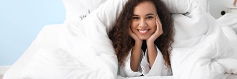 een vrouw die in bed ligt met haar handen op haar gezicht