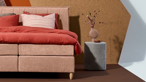 een bed met een vaas met bloemen